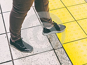 Closeup shot of male feet stepping on yellow sidewalk tiles