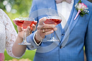 Closeup shot of a male and a female holding glasses with red-colored cocktails