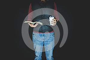 Closeup shot of a male holding coffee and the bible with a black background