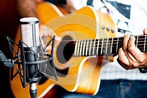 Closeup shot of a male playing guitar and recording music at home