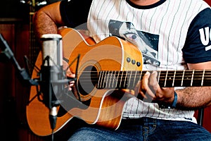 Closeup shot of a male playing guitar and recording music at home