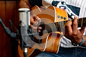 Closeup shot of a male playing guitar and recording music at home