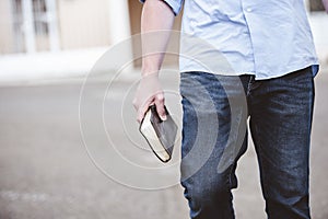 Closeup shot of a male walking while holding the bible