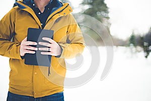 Closeup shot of a male wearing a yellow jacket and holding the bible against his chest
