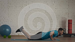 Closeup shot. Man fitness coach in sportswear doing knee push ups exercise for online class at the home studio.