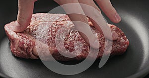 Closeup shot of man hands put ribeye steak on non stick pan