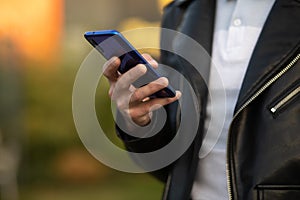 Closeup shot of an man holding mobile phone in hand, blurred background