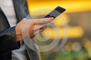 Closeup shot of an man holding mobile phone in hand, blurred background