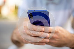 Closeup shot of an man holding mobile phone in hand, blurred background