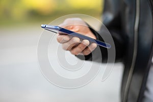 Closeup shot of an man holding mobile phone in hand, blurred background