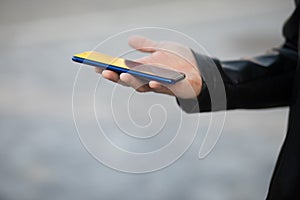 Closeup shot of an man holding mobile phone in hand, blurred background