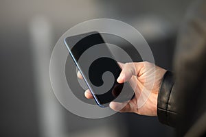 Closeup shot of an man holding mobile phone in hand, blurred background