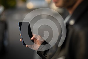 Closeup shot of an man holding mobile phone in hand, blurred background