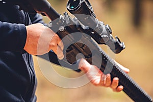 Closeup shot of a man holding the shooting gun at an outdoor shooting range