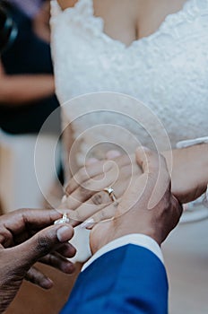 Closeup shot of a man putting a ring on his bride's finger