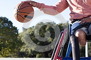 Closeup shot of man in wheelchair dribbling basketball