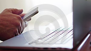 Closeup shot of a man working with a laptop and using the phone simultaneously