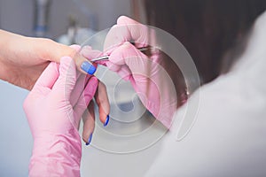 Closeup shot of manicurist in pink rubber gloves makes hand painting fingernails with brush