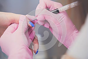 Closeup shot of manicurist in pink rubber gloves makes hand painting fingernails with brush