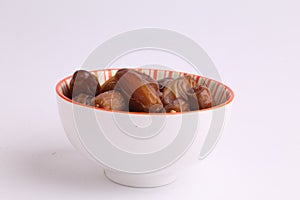 Closeup shot of medjool dates in a bowl on a white background