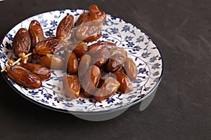 Closeup shot of medjool dates in a decorative plate  on a black surface