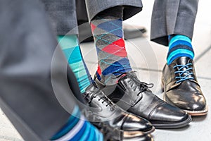 Closeup shot of men wearing patterned colorful socks with suits and classy shoes