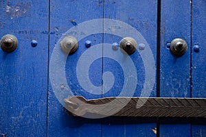 Closeup shot of the metal bolts and handle on a blue wooden door