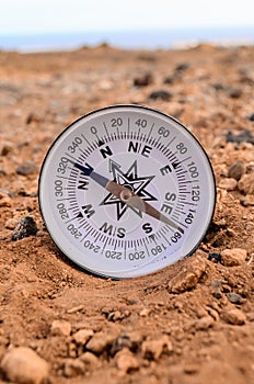 Closeup shot of metal compass on a rock in the desert - orientation concept