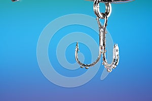 Closeup shot of a metal hook with water droplets on a blue background