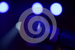 Closeup shot of a microphone set on a stage during an event with lights in the background