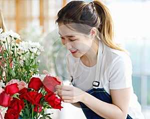 Closeup shot of Millennial Asian young professional female shopkeeper decorator florist wearing jeans apron standing smiling