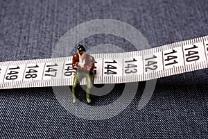 Closeup shot of a miniature figure sitting on centimetre isolated on the gray background photo