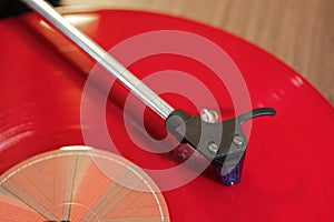 Closeup shot of a modern gramophone with a red disc and headshell in a blurred background