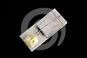 Closeup shot of a mousetrap with cheese on a black background