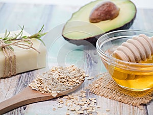 Closeup shot of natural skincare product ingredients: avocado, honey, oat flakes, and natural soap