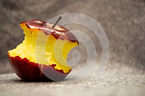 Closeup shot of a nearly eaten red apple on a gray fabric background