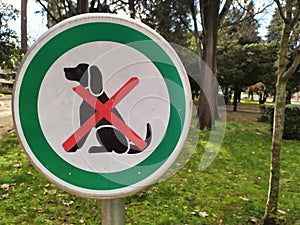 Closeup shot of the no dogs allowed sign on the park entrance area on a gloomy day