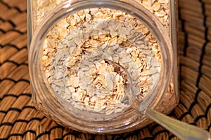 Closeup shot of oat flakes with a spoon in a glass container