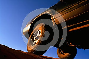 A closeup shot of a offroad racing car powering through a deep muddy hole its wheels spinning at speed. Speed drive