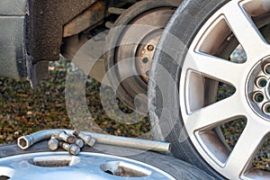 Closeup shot og tire bolts and aluminiumwrench with summer and winter tires and brake disc in the background.