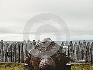 Closeup shot of an old canon in Bulnes Fort, Punta Arenas, Chile with wooden fence and sea