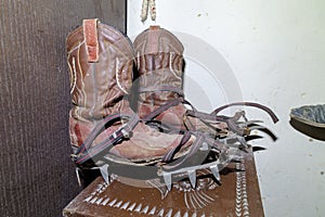 A closeup shot of old dusty cowboy boots with steel crampons for ice climbing
