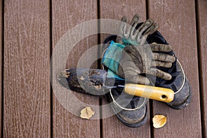 Closeup shot of old shoes, gloves, and shovel on a wooden surface