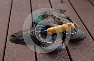 Closeup shot of old shoes, gloves, and shovel on a wooden surface