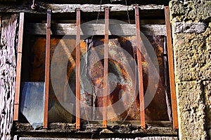 Closeup shot of an old window of a stone building with rusty metal fence