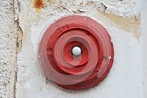 Closeup shot of an old worn and disused red doorbell