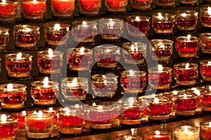 Closeup shot oof rows of burning candles in a church