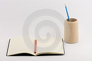 Closeup shot of an open blank book with a pencil cup isolated on white background