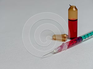 Closeup shot of an open glass ampule and syringe filled with a red liquid and copy space