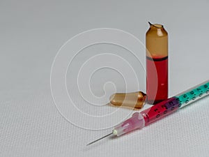 Closeup shot of an open glass ampule and syringe filled with a red liquid and copy space